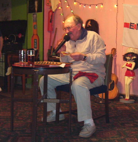 Gordon Cragg seated at bingo table reading a note written on a bear mat